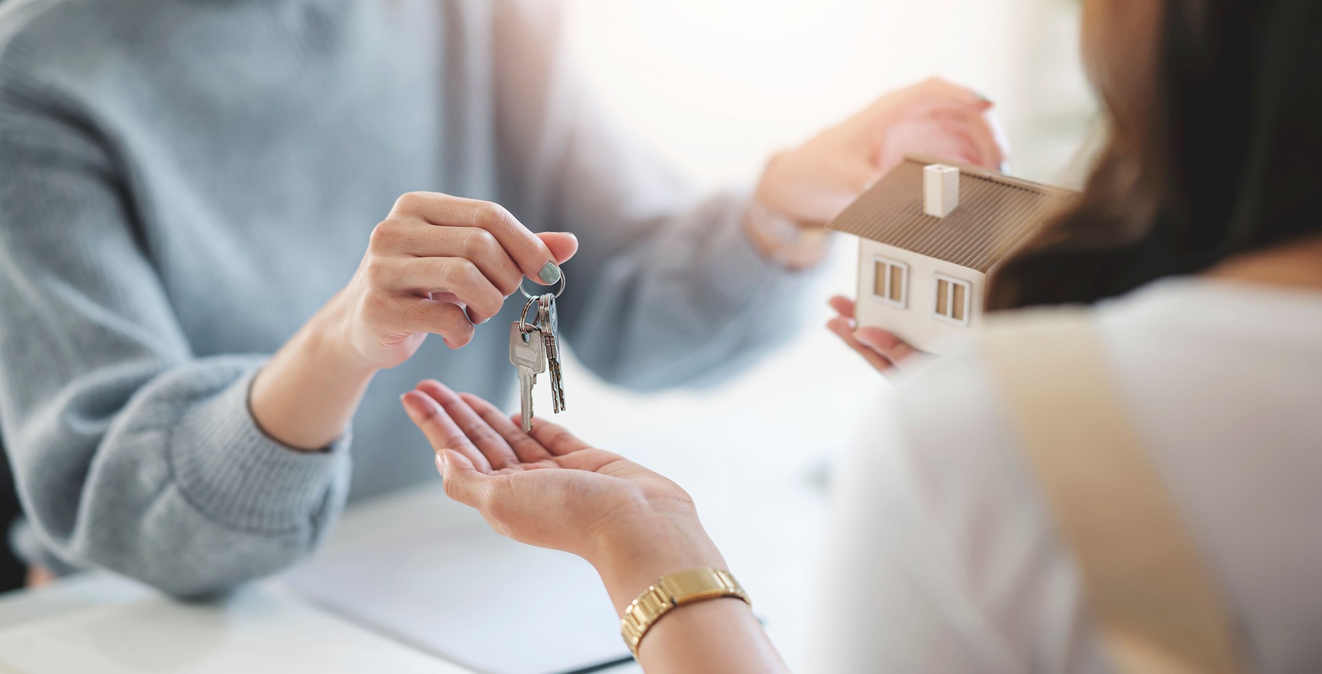 Buying real estate and agreement concept. Real estate agents agree to buy a home and give keys to clients at their agency's offices.